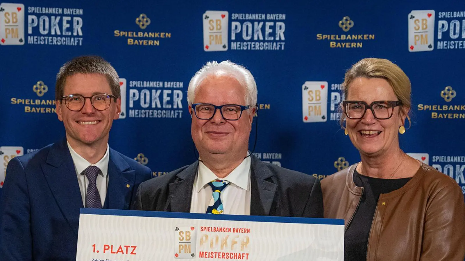 Ein Spieler mit dem Spitznamen Fisheater (Mitte) ist bayerischer Pokermeister 2026. Den Titel holte er sich beim Finale in der Spielbank Feuchtwangen.  (Foto: Staatliche Lotterie- und Spielbankverwaltung)