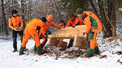 Gemeinsam anpacken: Die Auszubildenden stellten die neue Bank mit ihrem Meister Hartmut Kolsch (hinter der Bank, Mitte) im Wald zwischen Heilsbronn und Petersaurach auf. (Foto: Antonia Müller)