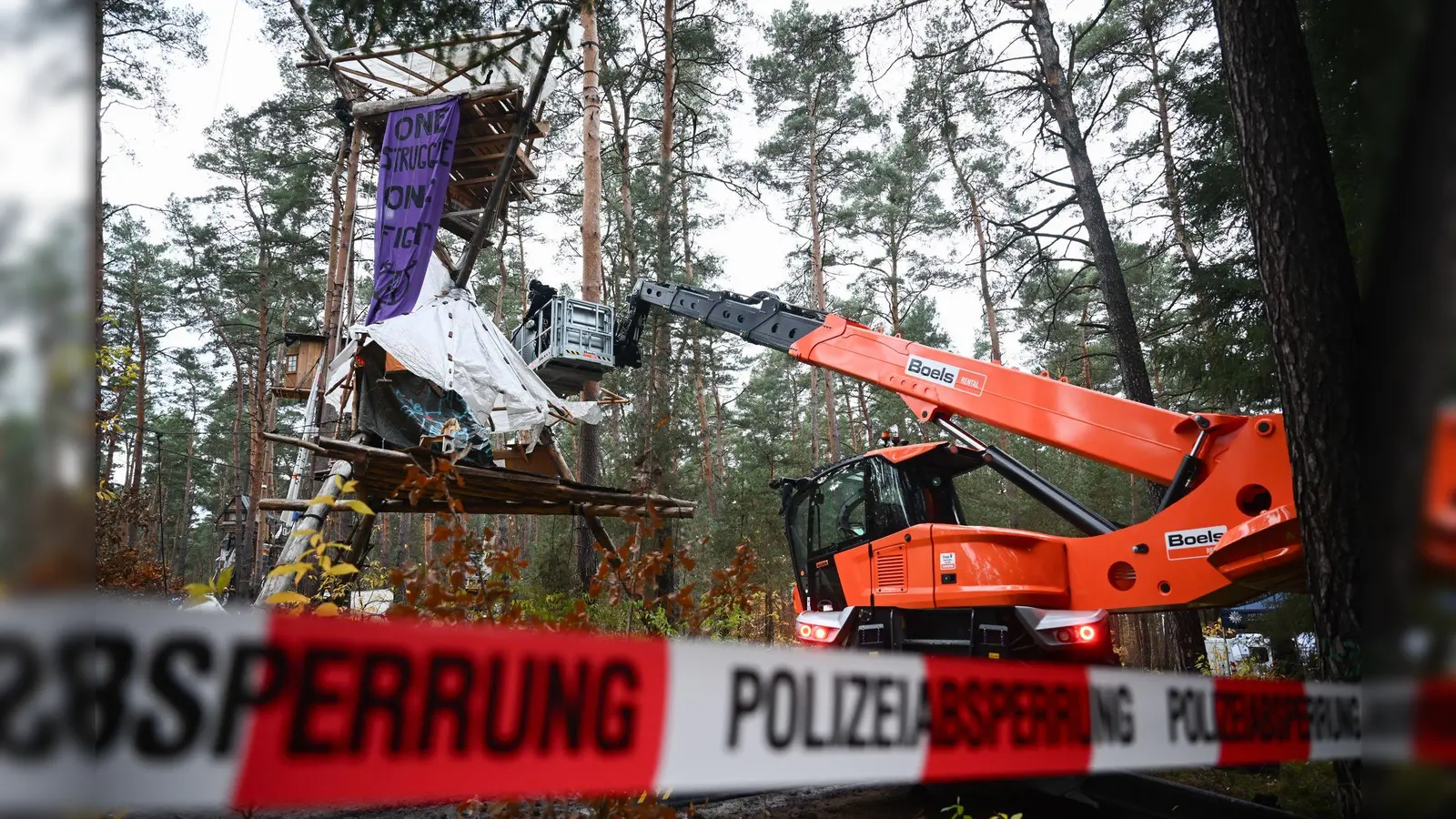 Mit Hilfe einer Hebebühne kommen die Polizeikräfte an die Baumhäuser im aufgelösten Tesla-Protestcamp heran.  (Foto: Sebastian Christoph Gollnow/dpa)