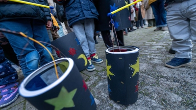 Kinder zeigen ihre gebastelten Laternen.  (Foto: Pia Bayer/dpa)