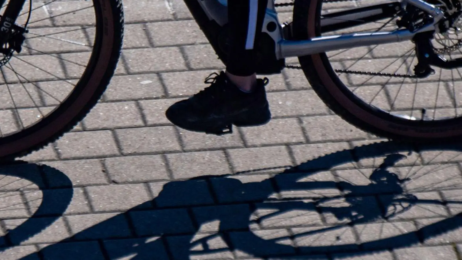 Eine Radfahrerin wirft einen Schatten. (Foto: Stefan Sauer/dpa/Symbolbild)