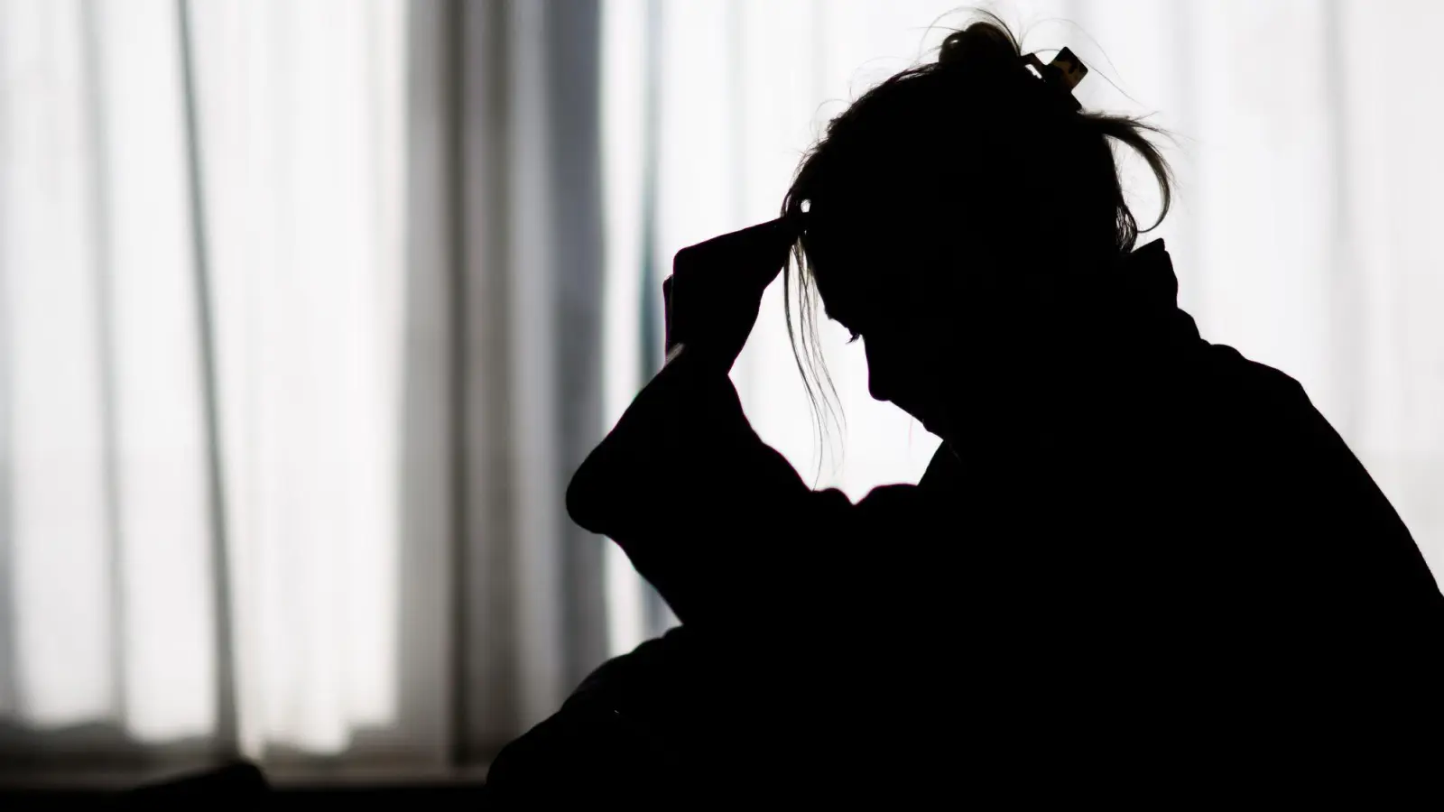 Silhouette einer Frau vor einer hellen Fensterfront (Foto: Julian Stratenschulte/dpa)