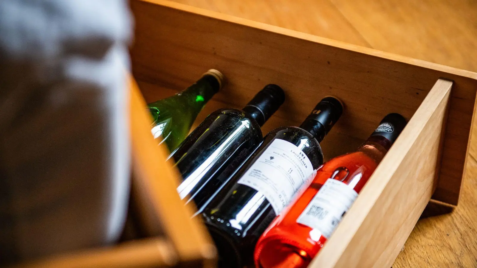 Da liegen sie gut: Weinflaschen lagern in einem Bettkasten im Schlafzimmer - ohne große Temperaturschwankungen.  (Foto: Zacharie Scheurer/dpa-tmn)