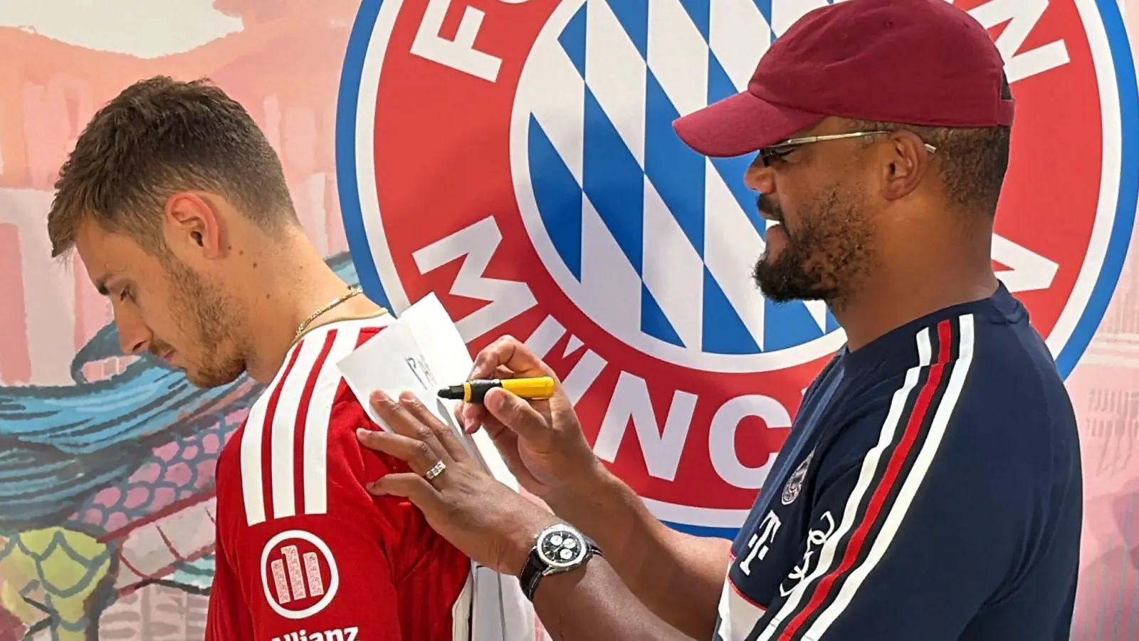 Trainer Vincent Kompany (r) malt - und Josip Stanisic muss raten.  (Foto: Christian Kunz/dpa)