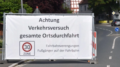 An den beiden Ortseinfahrten (im Foto von Osten kommend) auf der ehemaligen Bundesstraße in Markt Bibart stehen mitten auf der Fahrbahn große Transparente, die auf die neue Verkehrssituation hinweisen. (Foto: Andreas Reum)