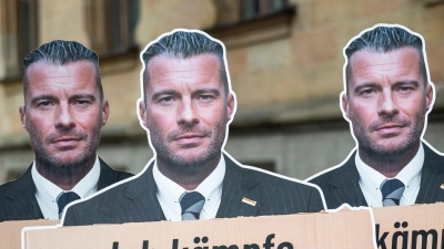 Vor dem Landgericht Bamberg stehen Pappaufsteller, die den Journalisten David Bendels mit einem Schild in der Hand zeigen - er bezeichnete seinen Post als Satire. (Foto: Daniel Vogl/dpa)