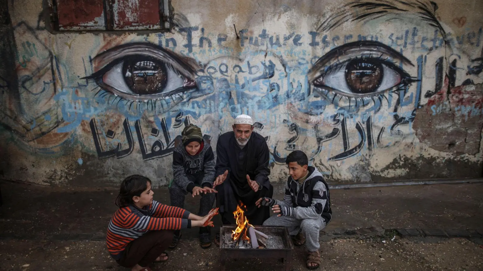 Palästinensische Kinder wärmen sich mit ihrem Großvater an einem Feuer in Gaza-Stadt (Archiv). (Foto: Wissam Nassar/dpa)