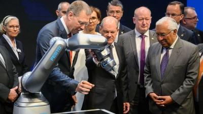 Bundeskanzler Olaf Scholz (M, SPD) und Antonio Costa (r), Premierminister von Portugal, betrachten neben Oliver Jung, Vorstandsvorsitzender Festo beim Eröffnungsrundgang auf der Hannover Messe 2022 einen Roboter mit pneumatischem Antrieb. (Foto: Julian Stratenschulte/dpa)