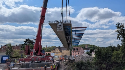 Mit einem Mobilkran wurden die Fertigteile für die neue Brücke auf die Widerlager gehoben. Rund 43 Tonnen wiegt eines der 26,5 Meter langen Elemente.  (Foto: Staatliches Bauamt Ansbach)