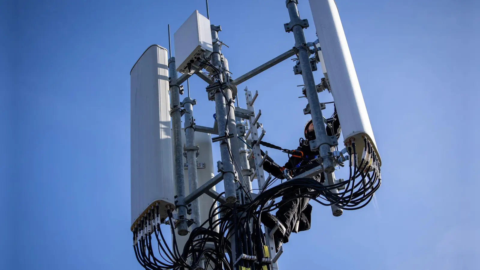 Einer von Zehntausenden Mobilfunk-Masten in Deutschland - hier einer, an dem gerade ein Techniker arbeitet. (Foto: Daniel Karmann/dpa)