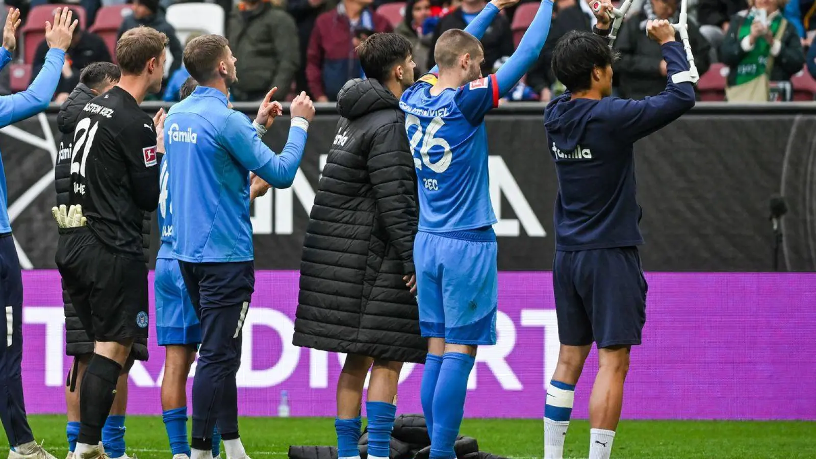 Holstein Kiel feiert den Sieg in Augsburg mit den mitgereisten Fans (Foto: Armin Weigel/dpa)