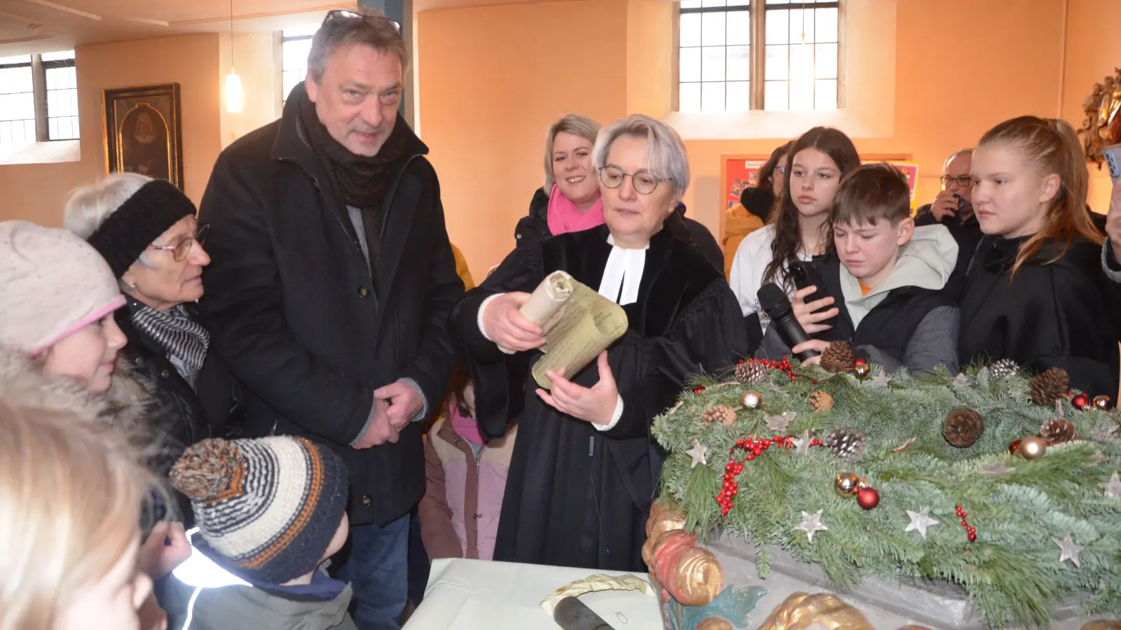 Die Münzen fielen als erstes aus der Blechrolle. Bürgermeister Detlef Genz und Pfarrerin Ines Weimann waren gespannt. Die Kinder kannten die Mark-Stücke nicht. Die Pfarrerin las den Zuschauern vor, was auf den Papierstücken so alles zu lesen war. (Foto: Christa Frühwald)