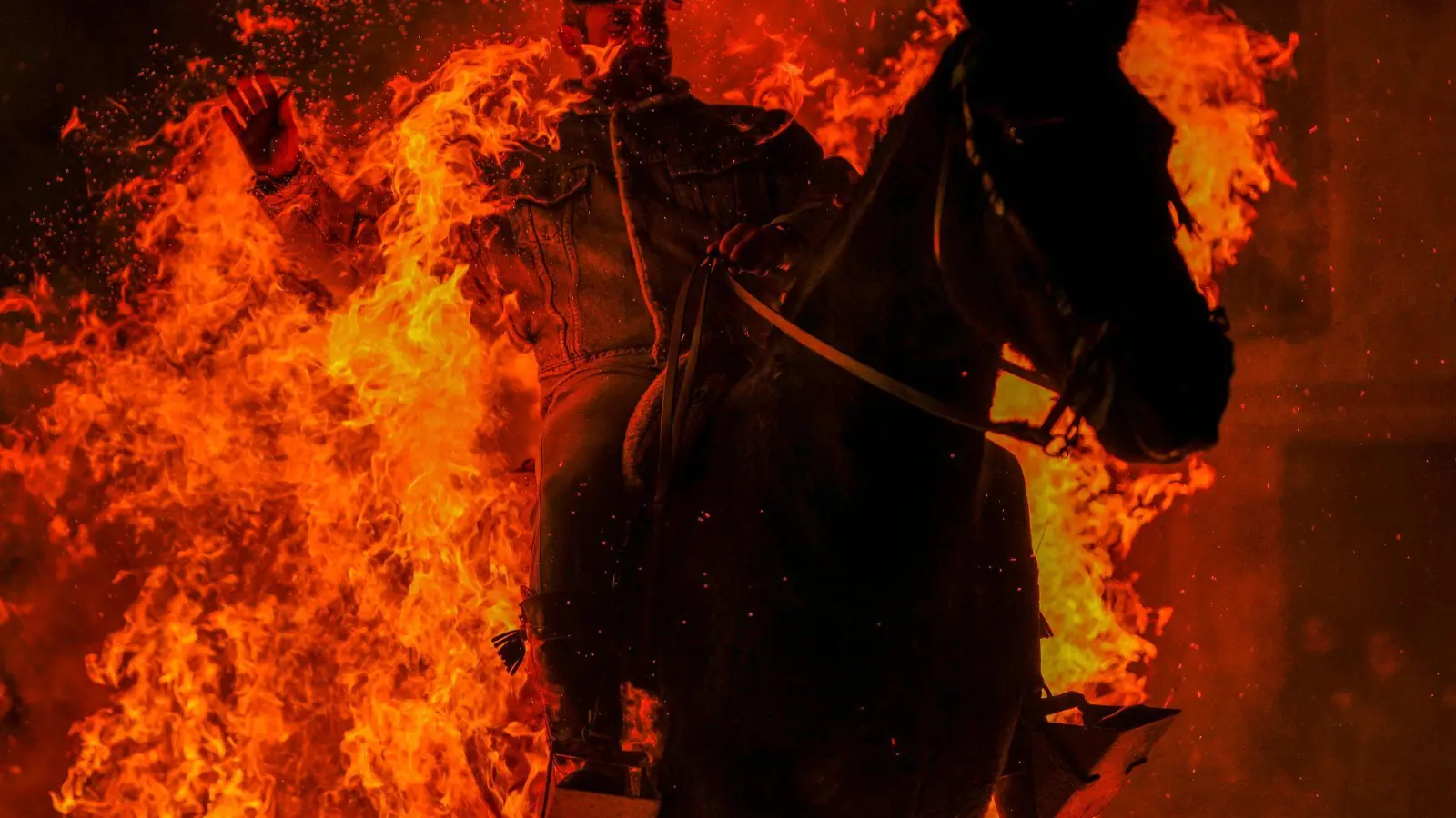 Feuriges Ritual: Mann reitet zu Ehren des Tier-Schutzpatrons durch Flammen (Foto: Manu Fernandez/AP/dpa)