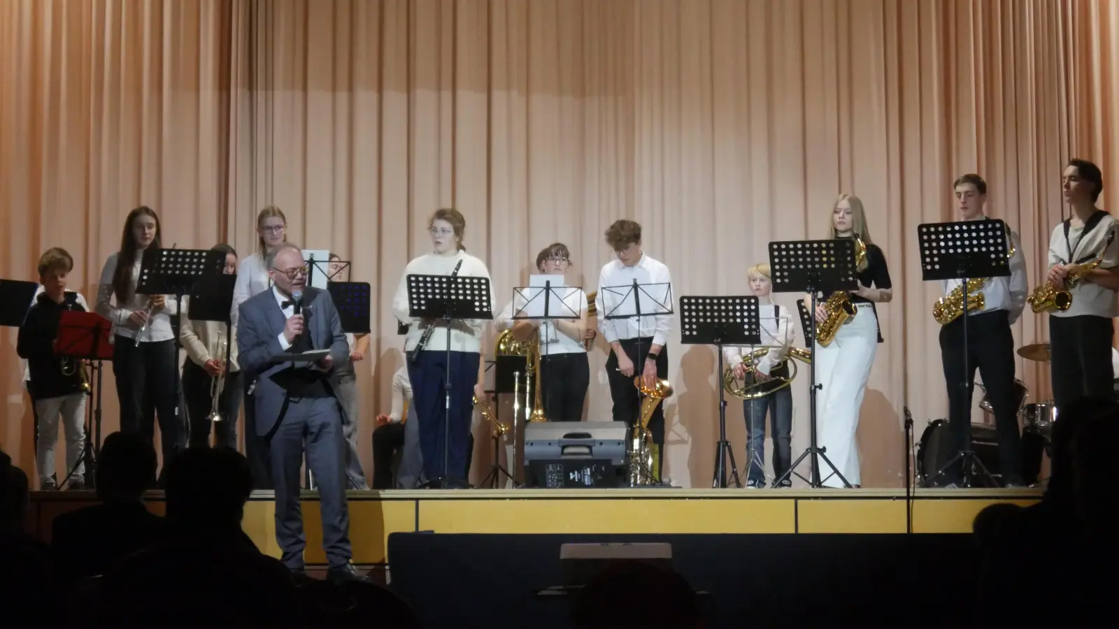 Schulleiter Wolfram Schröttel vor der schulischen Big Band bei seinen einleitenden Worten zur Jubiläumsfeier in der Wolfgang-Graf-Halle – eine kleine Spitze gegen den Bürgermeister hatte er dabei auch noch im Gepäck.  (Foto: Martina Hinkelmann)