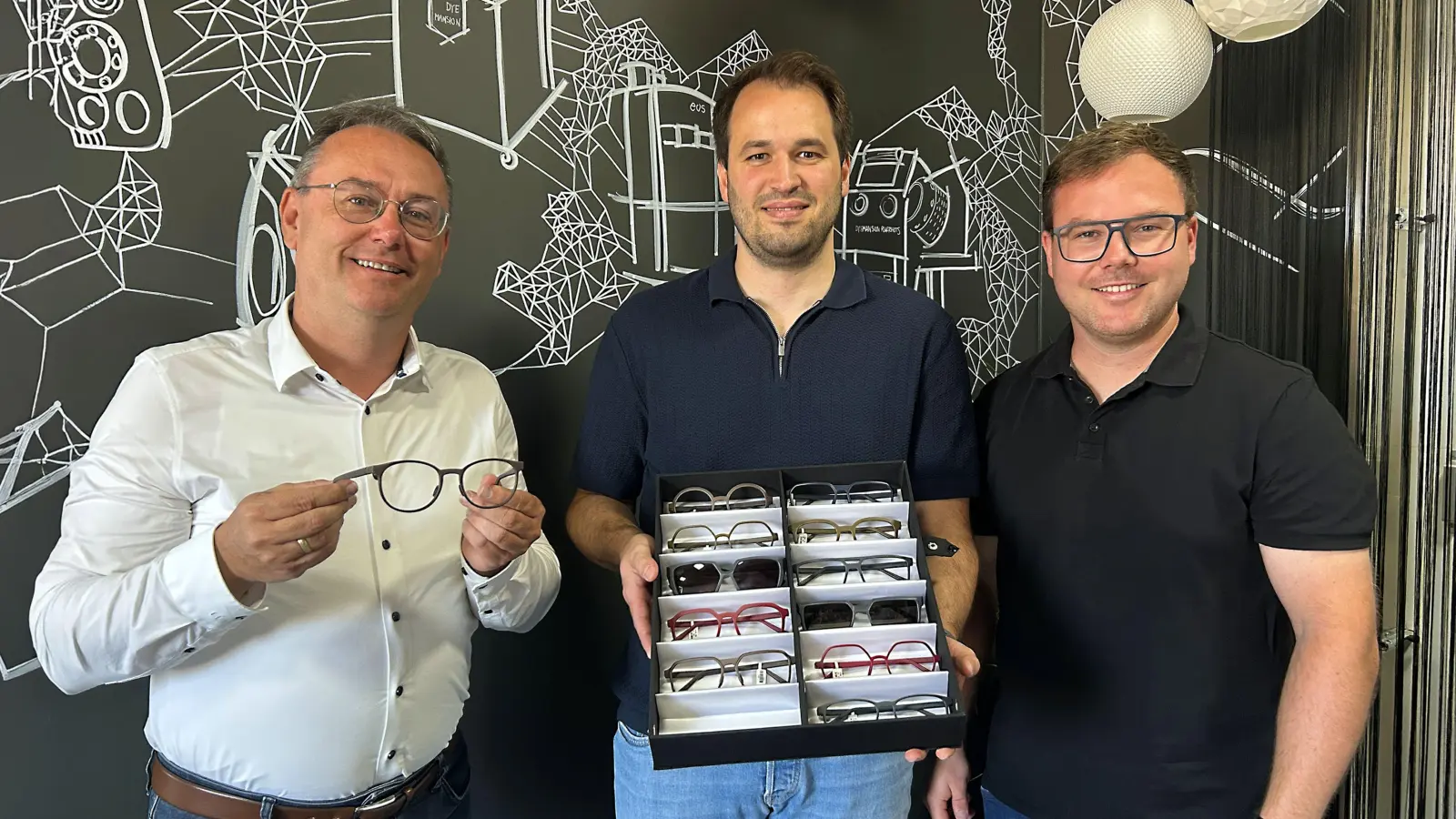 Der Vorsitzende der Lokalen Aktionsgruppe Region an der Romantischen Straße, Feuchtwangens dritter Bürgermeister Herbert Lindörfer, ließ sich von Alexander Bahle (rechts) und Tim Riedmüller (Zweiter von rechts) die Brillenkollektion zeigen.  (Foto: LAG/Julia Ploch)