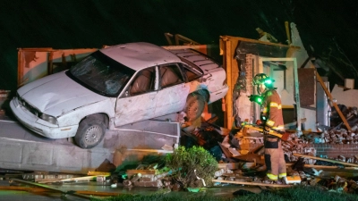 Ein Feuerwehrmann aus Wichita steht vor einem stark beschädigten Auto und Haus in Andover, nachdem ein Tornado durch das Gebiet östlich von Wichita gezogen ist. (Foto: Travis Heying/The Wichita Eagle/AP/dpa)