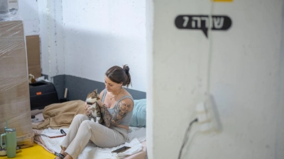Zwischen Alltag und Alarm - Katze und Frau suchen während eines Raketenangriffs Zuflucht im Parkhaus (Foto: Ilia Yefimovich/dpa)