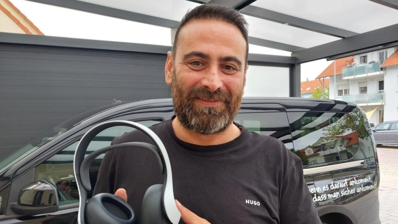 Hurman Tuncay zeigt die Kopfhörer, die sein Sohn von Andrew Garfield geschenkt bekommen hat. Im Hintergrund ist eines seiner Taxen zu sehen, Toni's ViP-Shuttle ist beim Fototermin unterwegs.  (Foto: Katrin Merklein)