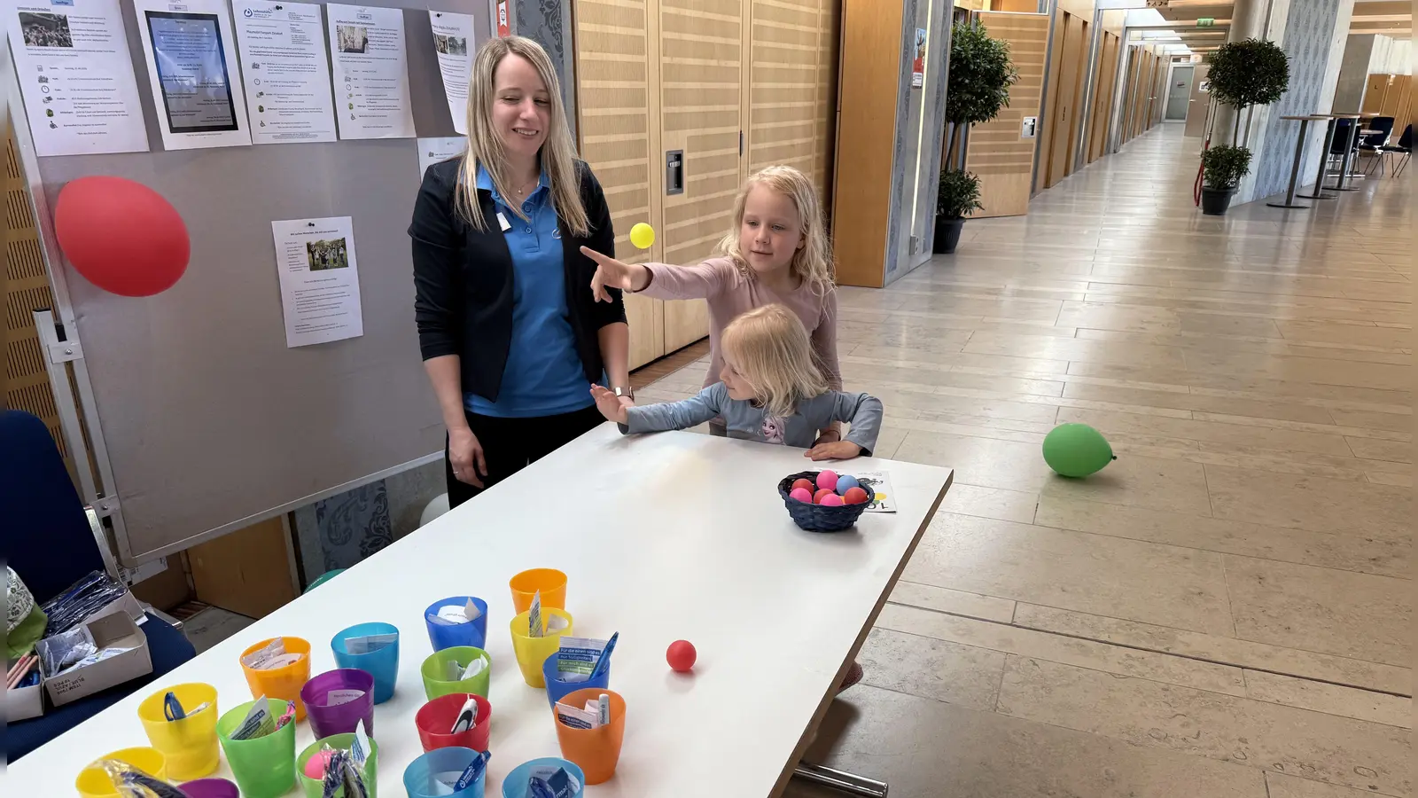Elise (blau) und Emma (rosa) hatten ihren Spaß damit, beim Lebenshilfe-Protesttag mit den Bällchen in die aufgestellten Becher zu treffen, deren Inhalt jeweils als Gewinn winkte. Nadine Ostmann von den Offenen Hilfen der Lebenshilfe schaute amüsiert zu. (Foto: Sylvia Fehlinger)