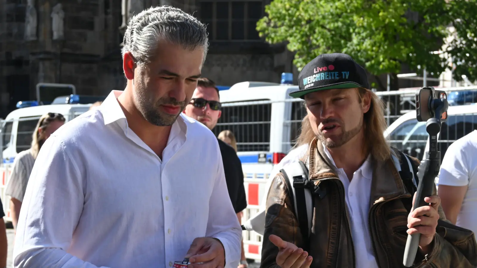Auf Seite der AfD sind immer wieder Personen zu sehen, die für Social Media filmen. Hier interviewt „Weichreite TV” (mit Kappe) gerade den Redner Irfan Peci für seinen Stream, der live auf YouTube übertragen wird. (Foto: Anna Beigel)
