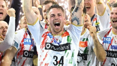 Magdeburgs Michael Damgaard jubelt mit der Trophäe dem dem Sieg gegen die Füchse Berlin in der Handball Champions League. (Foto: Marius Becker/dpa)