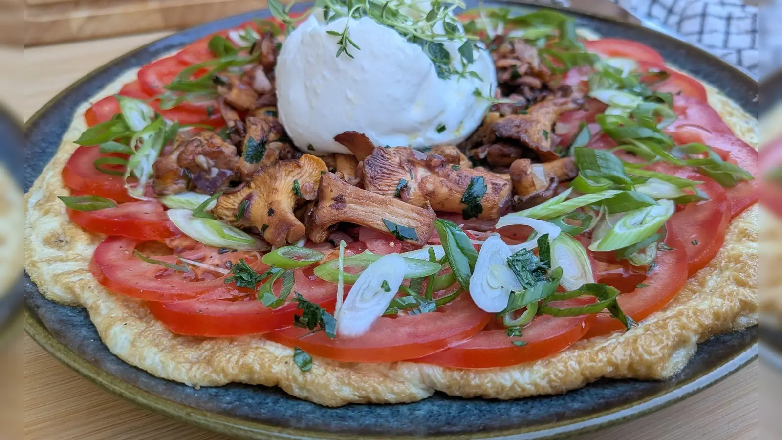 Sieht auf den ersten Blick aus wie eine Pizza, ist aber ein Omelett: Der Eierfladen wird mit Tomatenscheiben, gebratenen Pfifferlingen und Burrata belegt.  (Foto: Doreen Hassek/hauptstadtkueche.blogspot.com/dpa-tmn)
