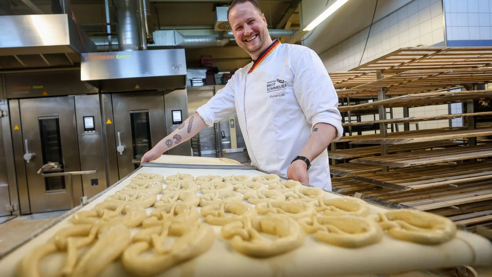 Backen ist Kunst: Brot-Sommelier Florian Lutz steht in seiner Backstube und schiebt ein Blech Brezeln in den Ofen. (Foto: Christoph Schmidt/dpa-tmn)