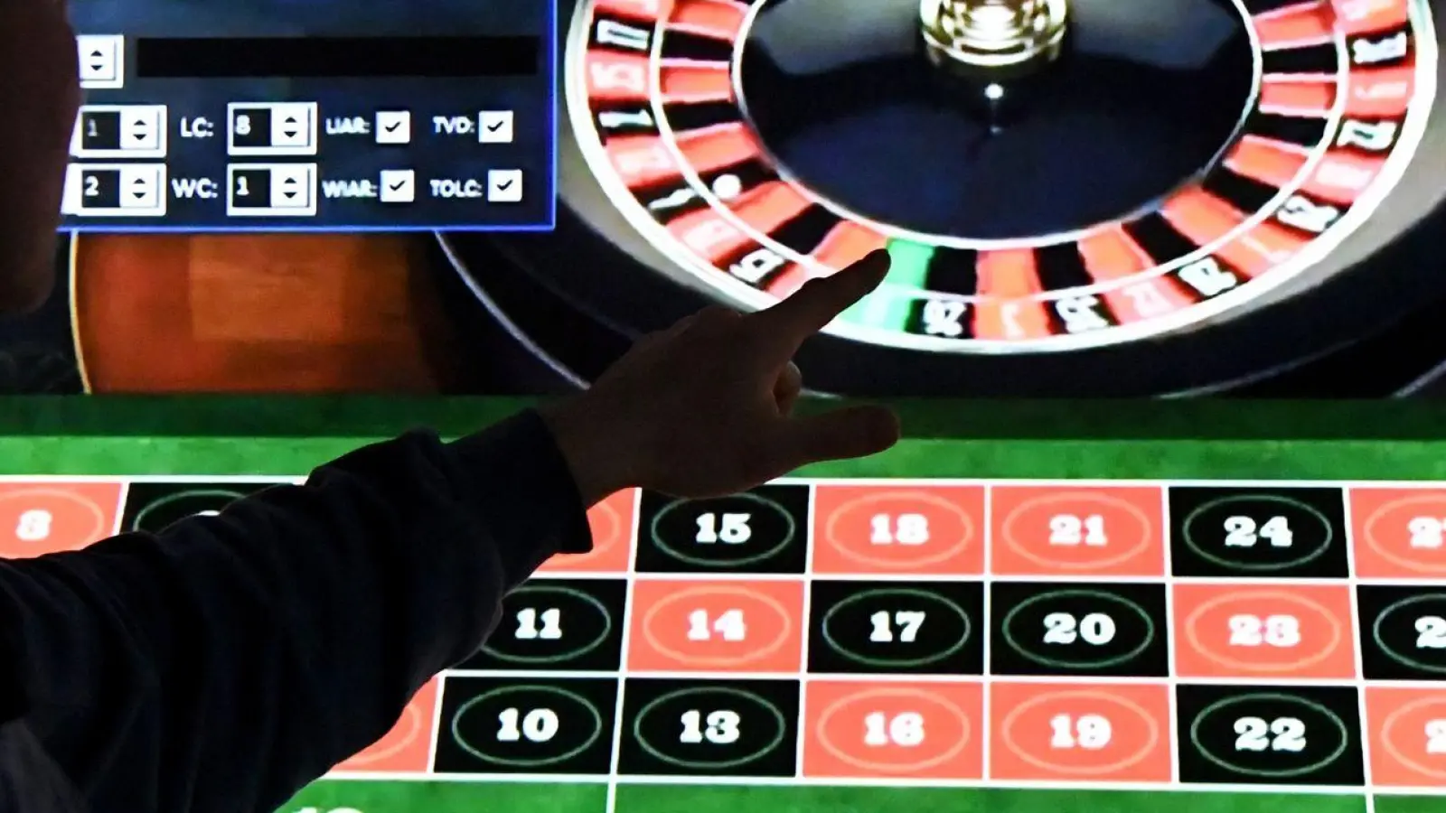 Ein Mann steht vor einem Bildschirm mit einer Seite für Online-Roulette. (Foto: Carsten Rehder/dpa/Archivbild)