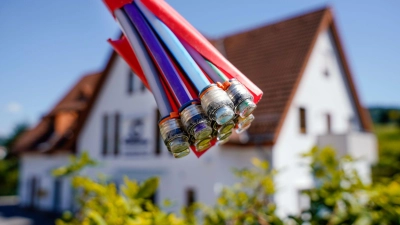 Ein Bündel mit Umhüllungen für Glasfaserkabel hängt vor einem Wohnhaus. (Foto: Uwe Anspach/dpa/Symbolbild)