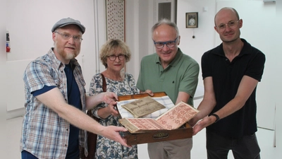 Robert Zöllner, Ulrike und Rudolf Weiß sowie Dr. Markus Rodenberg (von links) präsentieren das historische Webmusterbuch und das Vorschriftbüchlein. (Foto: Hans-Bernd Glanz)