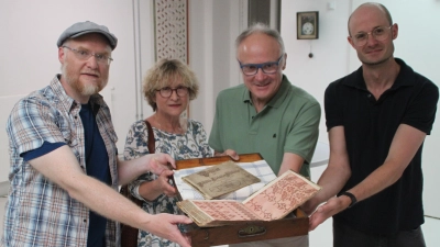 Robert Zöllner, Ulrike und Rudolf Weiß sowie Dr. Markus Rodenberg (von links) präsentieren das historische Webmusterbuch und das Vorschriftbüchlein. (Foto: Hans-Bernd Glanz)