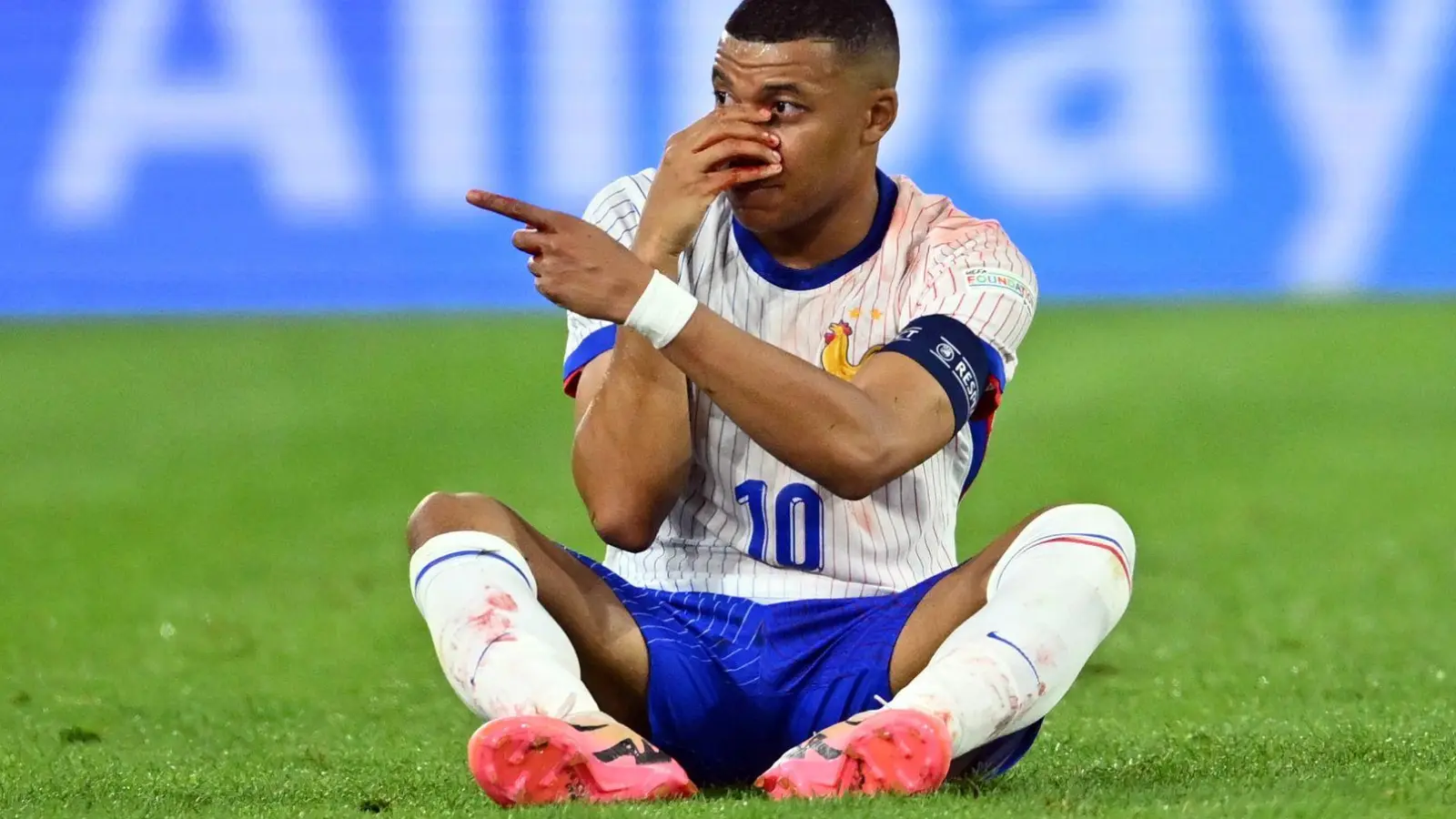 Diagnose Nasenbeinbruch: Frankreichs Kylian Mbappé sitzt beim Spiel gegen Österreich auf dem Rasen und hält seine verletzte Nase. (Foto: Marius Becker/dpa)