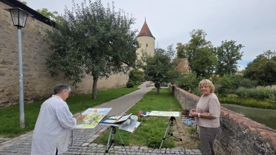 Petra Rackow (links) und Gaby Rühling malen am liebsten im Freien. Ihre Staffeleien haben die beiden Künstlerinnen mit Blick auf den Faulturm der Dinkelsbühler Wehranlage aufgebaut. Motiv und Lichtstimmung halten die beiden in Aquarell-Technik fest.  (Foto: Markus Weinzierl)