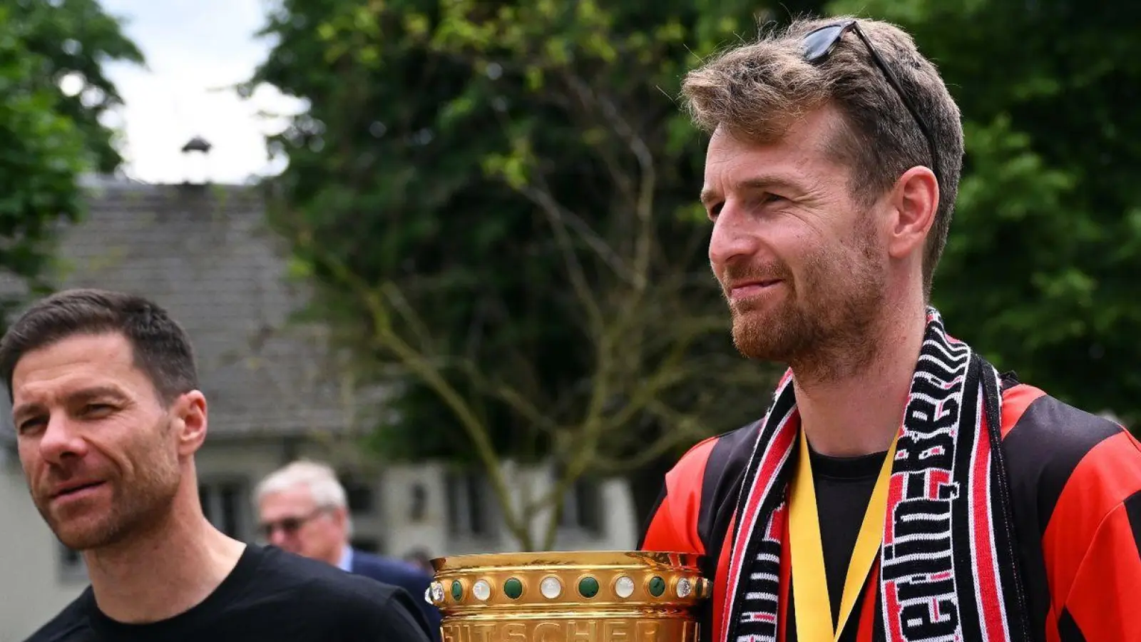 Leverkusens Trainer Xabi Alonso (l) und Leverkusens Torhüter Lukas Hradecky kommen mit dem Pokal zum Schloss Morsbroich, um sich in das Goldene Buch der Stadt einzutragen. (Foto: Marius Becker/dpa)