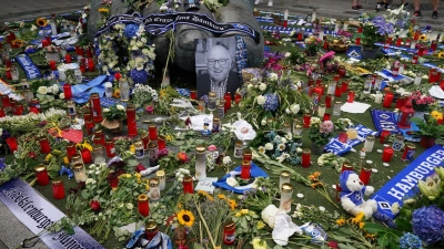 Ein Foto von Uwe Seeler und Blumen, Fan-Schals und Trauerlichter stehen an der Bronzeplastik vor dem Volksparkstadion. (Foto: Marcus Brandt/dpa)