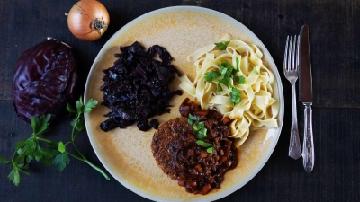 Ein luftiges Tagliatelle-Knäuel bildet mit weihnachtlichem Rotkraut und der krossen Veggie-Frikadelle ein Trio auf dem Teller. (Foto: Manfred Zimmer/herrgruenkocht.de/dpa-tmn)