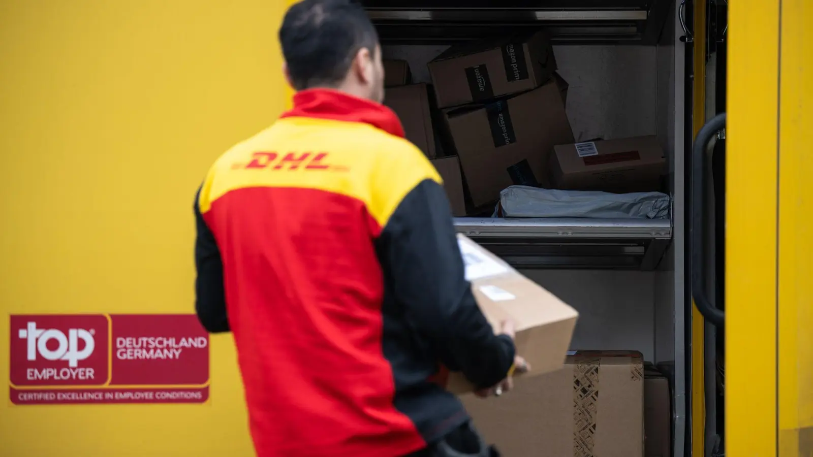 Ein Post-Mitarbeiter trägt ein Paket in einen Lieferwagen. (Foto: Hannes P. Albert/dpa)