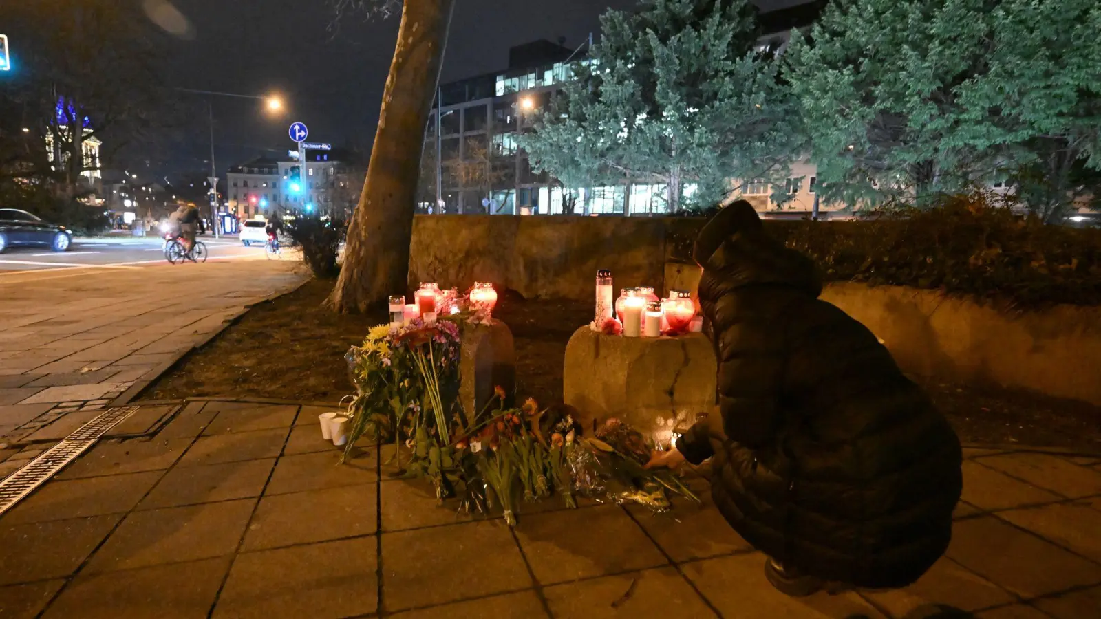 Eine Frau legt Blumen in der Münchner Innenstadt in der Nähe des Stiglmaierplatzes nieder, wo ein Auto in einen Demonstrationszug gefahren ist. Mehrere Menschen wurden zum Teil schwerst verletzt. (Archivbild) (Foto: Felix Hörhager/dpa)