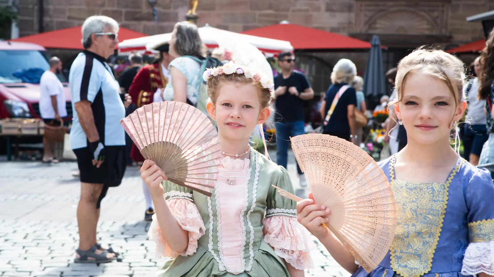 Je ein Fächer gegen die Hitze: Zwei junge Mädchen vom Heimatverein Ansbach wissen sich zu helfen. (Foto: Evi Lemberger)