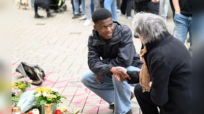 Suraj Mailitafi (l) von der Initiative „Gerechtigkeit für Lorenz“ spricht mit einer Passantin an dem Ort, an dem der 21-Jährige von der Polizei erschossen wurde.   (Foto: Izabela Mittwollen/dpa)
