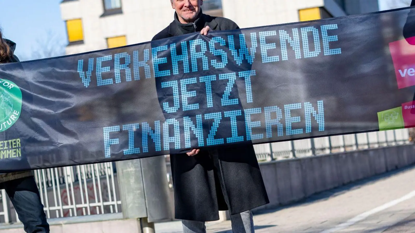 Emil Görtzen (l-r) von Fridays for Future, Jürgen Schirmer von Verdi und Patrick Steinbach vom Verkehrsbetrieb BoGeStra stehen mit einem Banner zum gemeinsamen Aktionstag vor der Verdi-Zentrale in Bochum. (Foto: Christoph Reichwein/dpa)