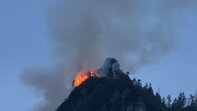 Noch immer steigen große Rauchwolken aus einem bewaldeten Berg bei Ruhpolding (Landkreis Traunstein) auf. (Foto: Matthias Brüning/dpa)