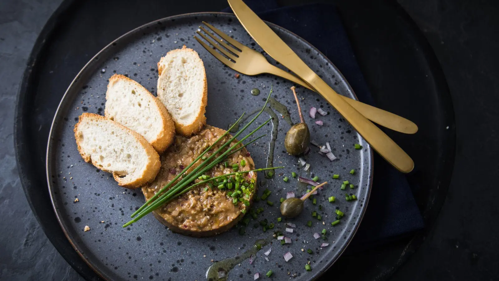 Die Form erinnert an einen Tatar-Taler. Doch er ist aus dem Fruchtfleisch der Aubergine mit Kapernäpfeln, Schnittlauch und Olivenöl zubereitet und kann mit Baguettescheiben gereicht werden. (Foto: Christin Klose/dpa-tmn)