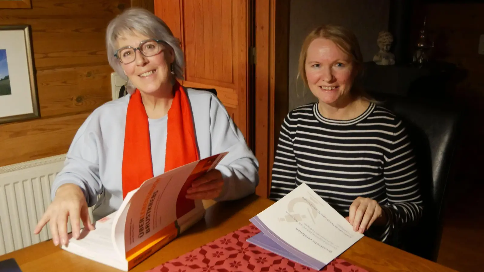 Edith Rabenstein (links) und Edeltraud Schmidt raten allen betroffenen Frauen, sich intensiv selbst mit der Erkrankung auseinanderzusetzen – zum Beispiel über ihre „Bibel“, wie sie sie nennen: das „Überlebensbuch Brustkrebs“ und die Broschüre „Brustkrebs verstehen“, die ihr eigener Verein herausgebracht hat. (Foto: Ulli Ganter)