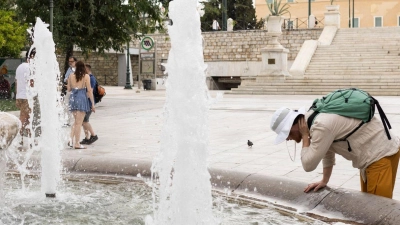 Ein Mann erfrischt sich an einem  Springbrunnen auf dem Athener Syntagma-Platz. (Foto: Socrates Baltagiannis/dpa)