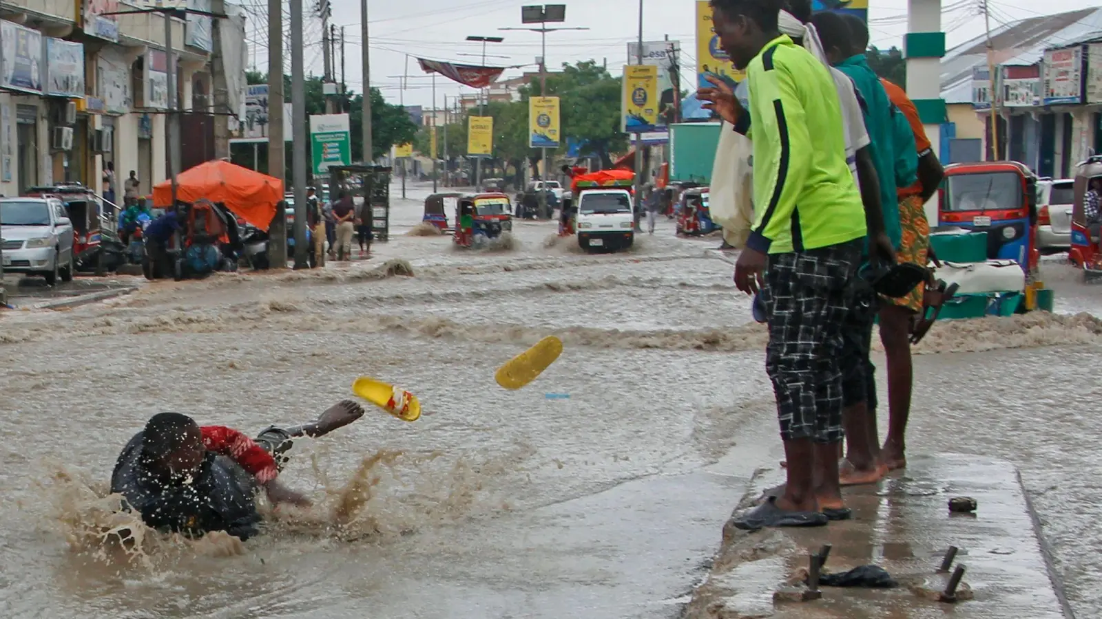 Ein Mann rutscht nach starken Regenfällen im Hochwasser aus. (Foto: Farah Abdi Warsameh/AP/dpa)