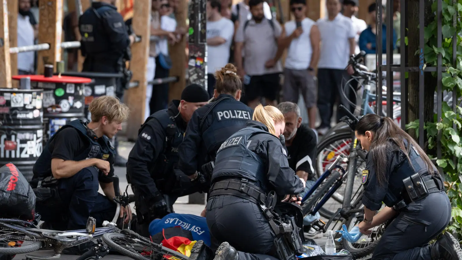 Polizisten knien in der Nähe des Frankfurter Hauptbahnhofs am Boden und kümmern sich um einen Verletzten.  (Foto: Boris Roessler/dpa)