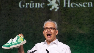 Tarek Al-Wazir erhält als Geschenk ein Paar Turnschuhe. Diese sollen an den ersten grünen Minister im hessischen Kabinett erinnern, der in Turnschuhen zur Vereidigung kam. (Foto: Thomas Frey/dpa)