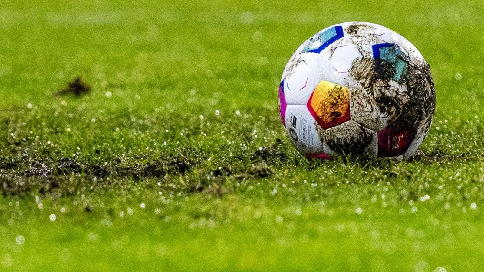 Ein Fußball liegt am Elfmeterpunkt im matschigen Rasen. (Foto: David Inderlied/dpa/Symbolbild)