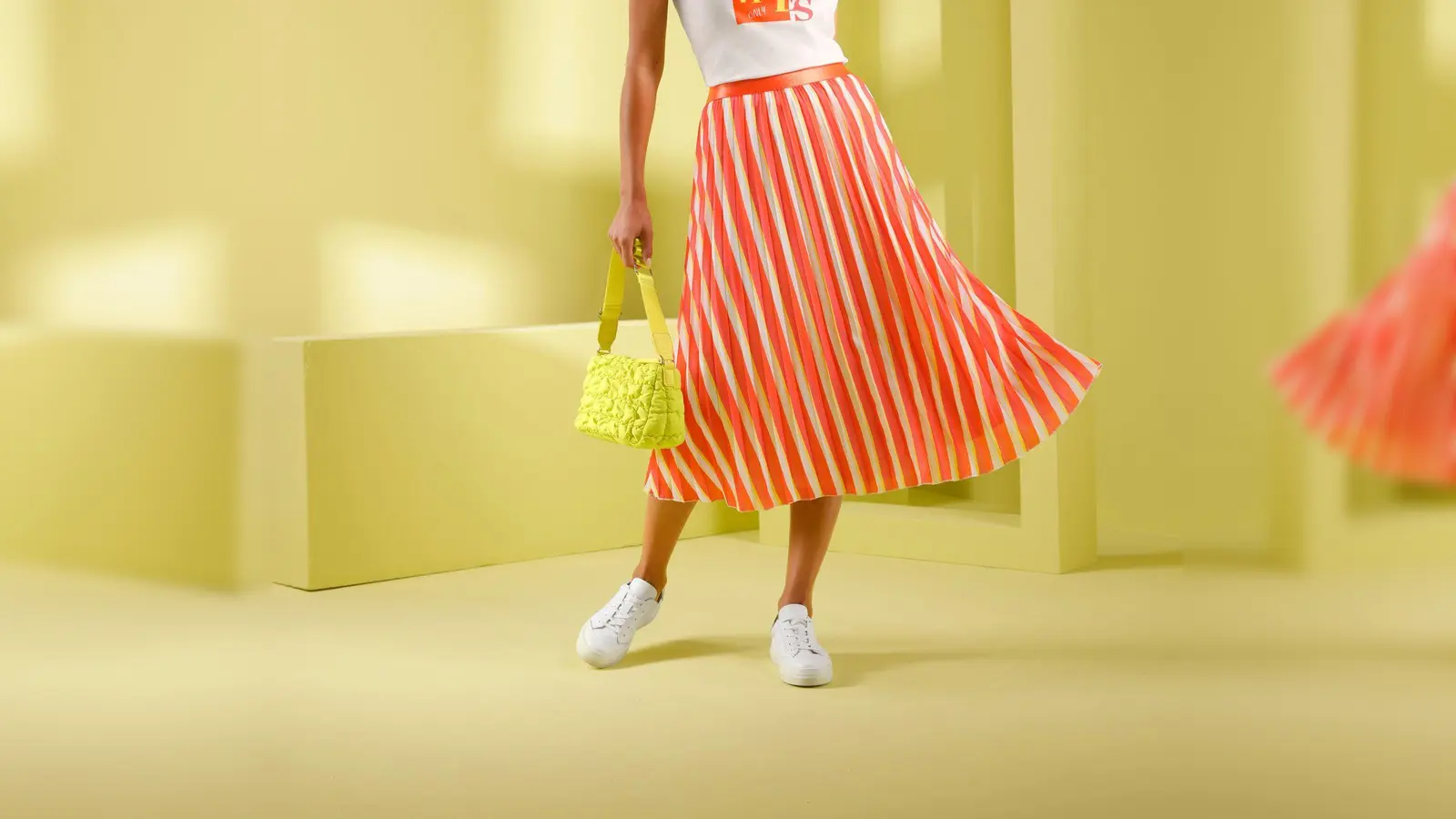 Gute-Laune-Kombi fürs Frühjahr: Gelb und Orange sind stark angesagt. Hier ein Beispiel von heine (Plissée-Rock ca. 60 Euro, Shirt ca. 30 Euro). (Foto: heine/dpa-tmn)